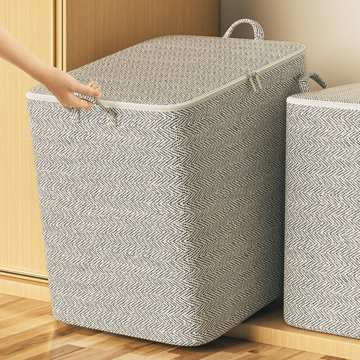Hand adjusting the top closure of a grey foldable zippered storage bag beside a wardrobe
